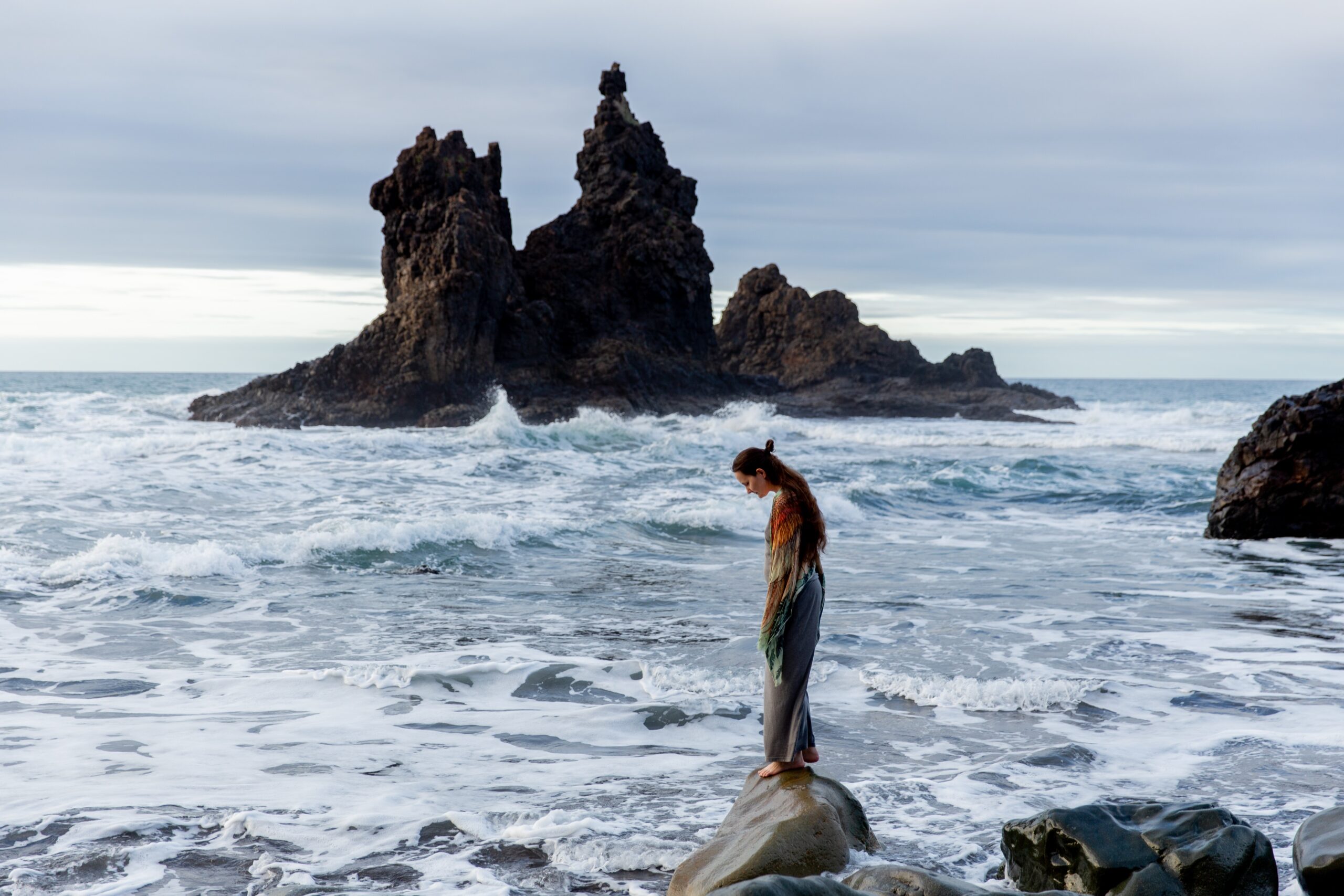 Woman standing on a rock looking at the ocean